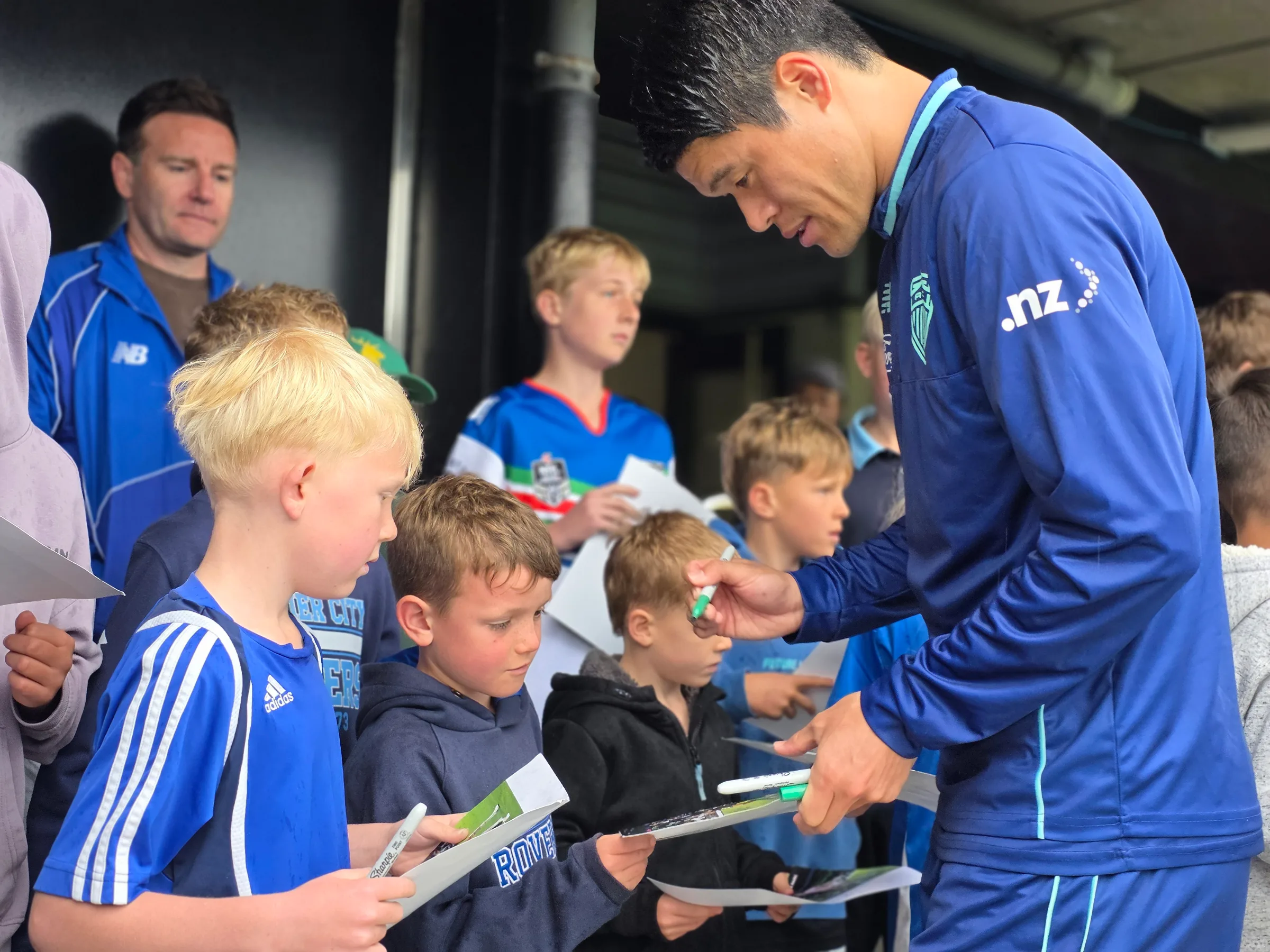 Auckland FC player Hiroki Sakai signs posters for fans at Napier's McLean Park.